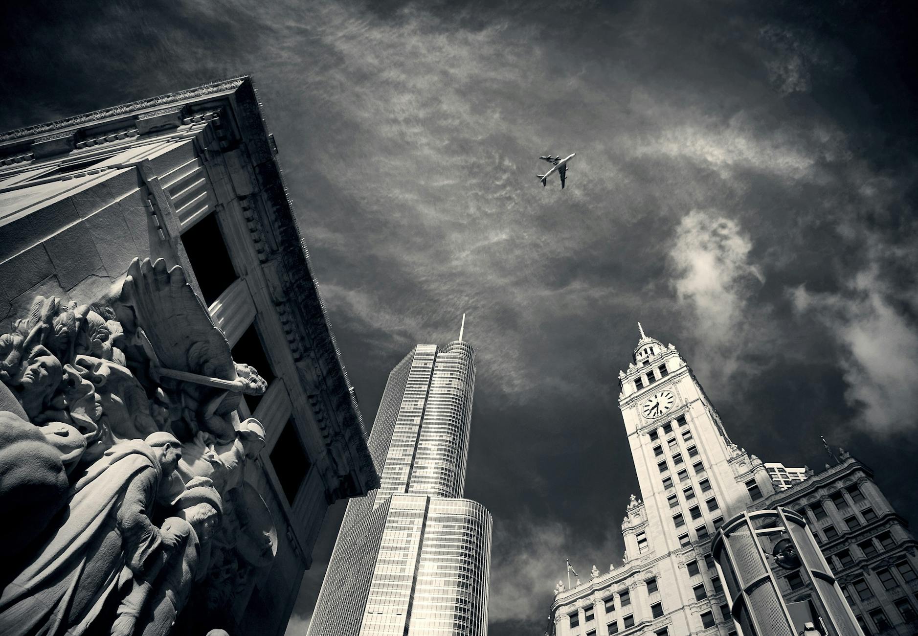 air plane flying over concrete buildings and statues in grayscale photography